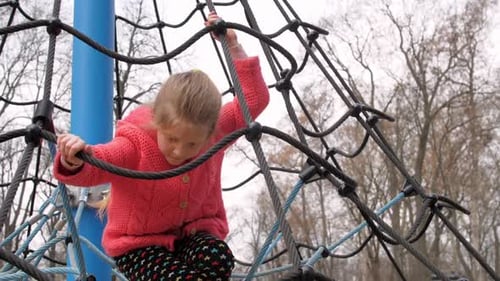 Young Girl Climbing on Rope Playground Structure