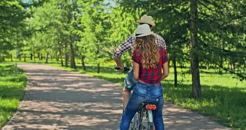Couple Rides Bicycle Together in Park on Sunny Day
