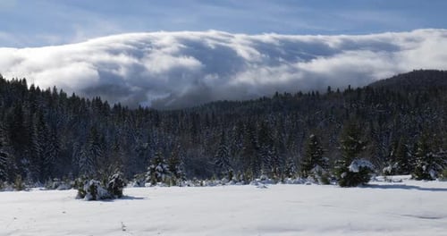 Schnelle Wolken, die an einem sonnigen Wintertag über den Berggipfel fließen