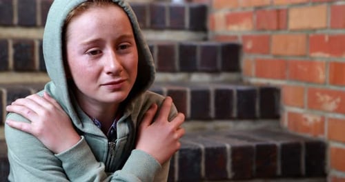 Sad schoolgirl sitting alone on staircase