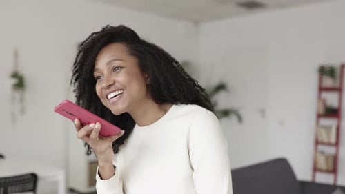 Smiling Woman Speaking Into Mobile Phone Indoors