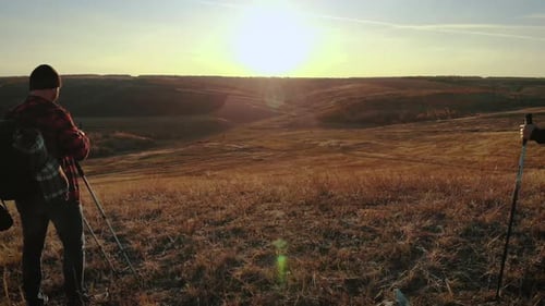Happy Couple Man and Woman Tourist at Top of Mountain at Sunset Outdoors During a Hike. Silhouettes