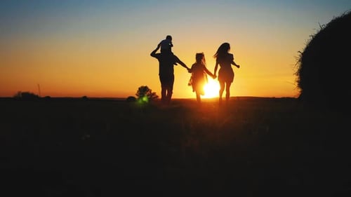 Family Silhouette Running in Golden Sunset Field