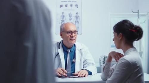 Doctor Consulting With Patient in Clinic Office