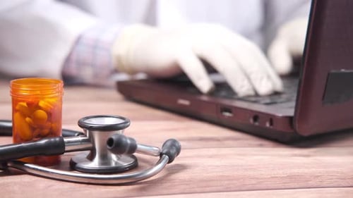 Doctor Typing on Laptop in Office with Pills