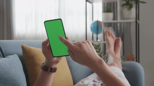 Hand Man At Home Lying On Couch In Living Room Using Smartphone With Green Screen Display