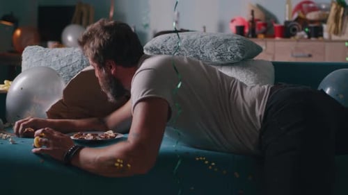 Hombre despertando en una habitación destrozada después de la fiesta