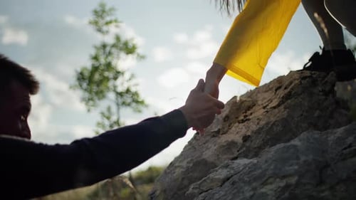 Closeup of a Girl Helping a Boy Climb a Rock