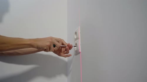 An Electrician Installs an Electric Socket Outlet Into Wall