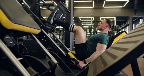A Young Pumped Up Athlete Does Another Leg Exercise In The Gym In Preparation For Competition.