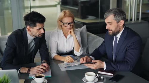 Business People Analyzing Financial Documents Working in Cafe During Lunch Break