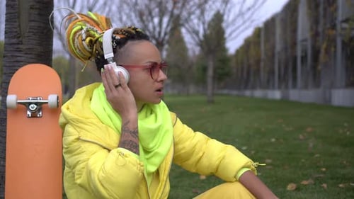 Young Adult Conversing with Headphones in Park