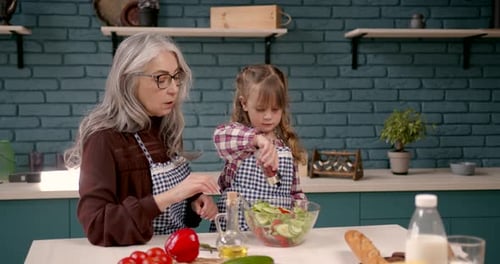 Grandmother and Child Making Salad in Kitchen