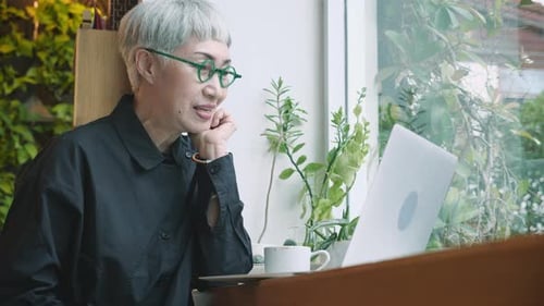 Mature Woman Engaged in Video Call on Laptop