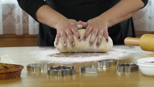 Nahaufnahme Weibliche Hände kneten Hefeteig auf dem mit Mehl bestreuten Tisch