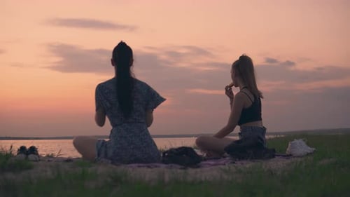 Two Women Enjoying Picnic At Sunset By Lake