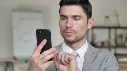 Focused Businessman Using Smartphone in Modern Office