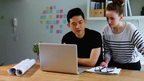 Young Adults Working Together on a Laptop in Office