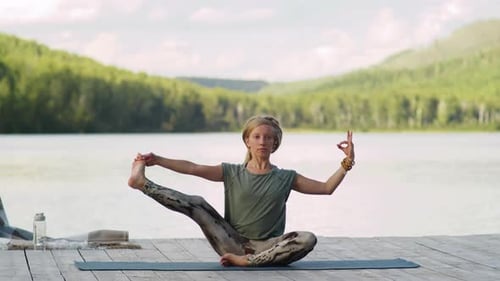 Woman Doing Yoga Leg Stretch on Wooden Pier by Lake