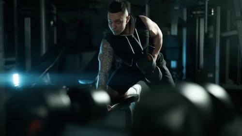 A Handsome Young Muscular Sportsman is Doing Exercise on a Fitness Machine in the Gym