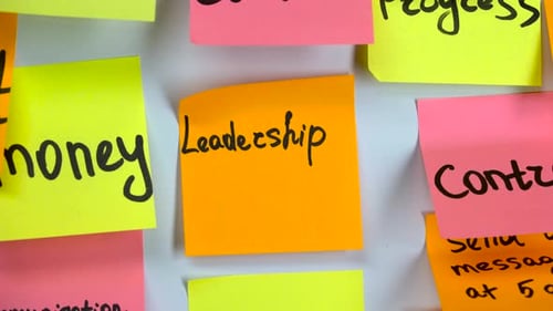Word Leadership Written on Orange Sticker Glue Board