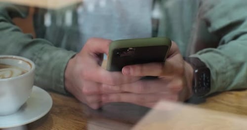 View Through Window of Businessman Chat on Smartphone in Coffee Shop