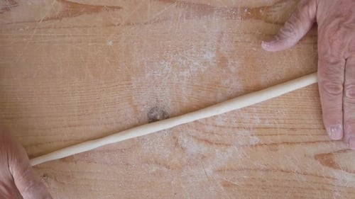 Hands Rolling Dough on a Floured Surface