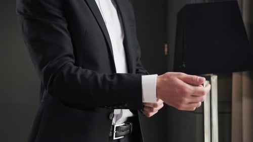 Businessman in Formal Suit Straightens the Cuffs of His Jacket in Hotel Room