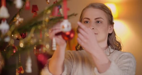 Woman Decorating Christmas Tree with Festive Ornaments