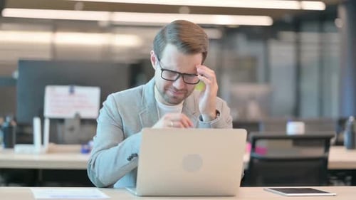 Adult Male at Computer Experiencing Headache in Office