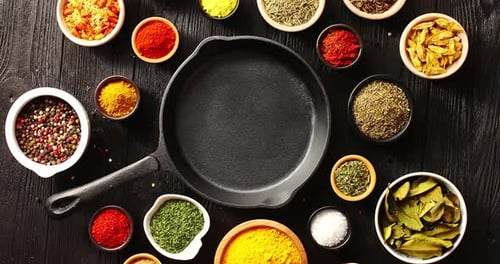 Spices and Herbs Arranged around Skillet on Table