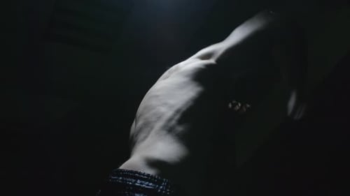 Shirtless Boxer Shadow Fighting in Darkness