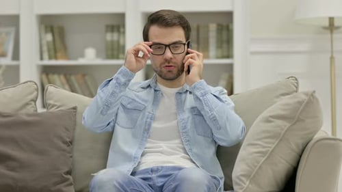 Man Sitting on Sofa Talking on Smartphone
