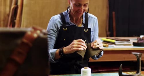 Craftswoman Sewing Dark Leather in Workshop