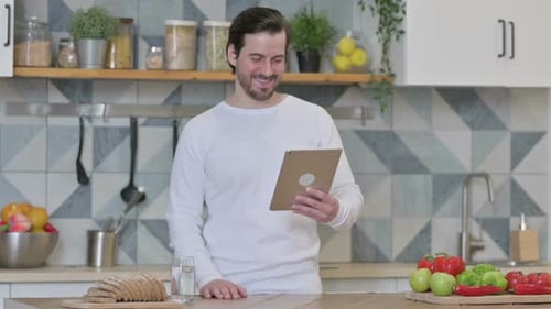 Bearded Man Uses Tablet in Kitchen