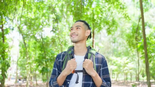Asian young handsome male backpacker traveling alone in forest wild on holiday vacation.