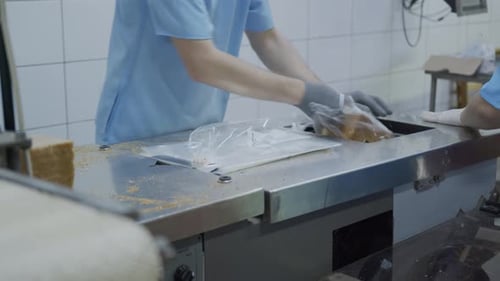Bakery Worker Packs Sliced Bread in Plastic Bags. Production and Packaging of Bread.