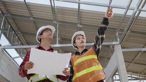 Architect and client discussing the plan with blueprint of the building at construction site