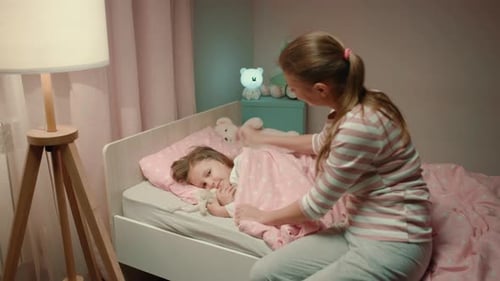 Mother Tucking Child in Bed at Night