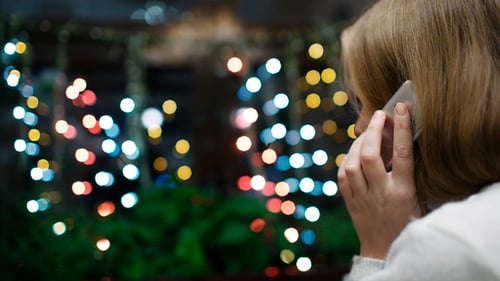 Woman Talking on Phone Near Blinking Christmas Lights