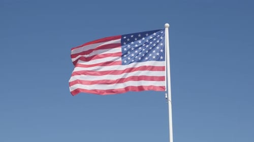 American Flag Waving on Pole Under Blue Sky