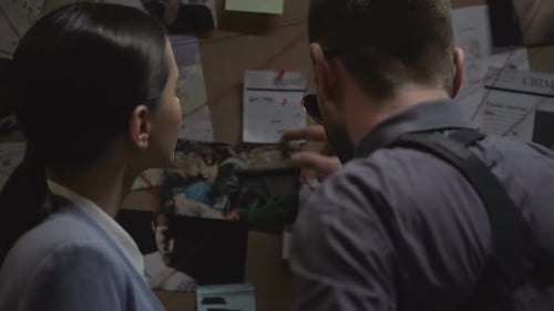 Detectives Discuss Evidence on Crime Investigation Board