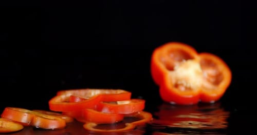 Schneidet süße rote Paprika, die mit einem Spritzer ins Wasser fällt.