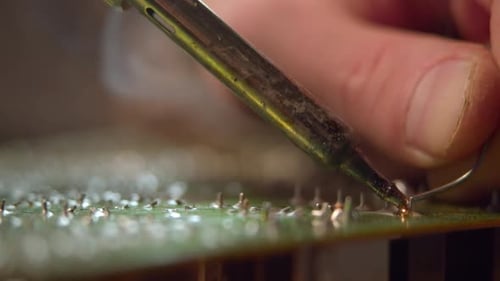 Worker Solders Wire to Circuit Board Using Tool in Workshop