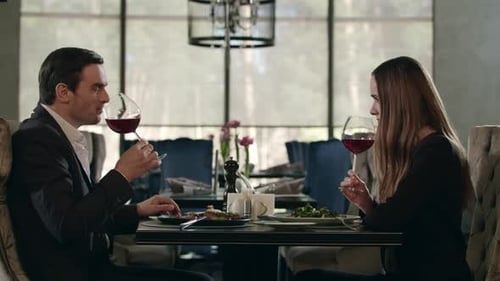 Man and Woman Tasting Red Wine at Restaurant Dinner. Couple Dining in Restaurant
