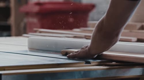 Carpentry Works Worker Slowly Cutting the Long Wooden Detail Using an Automatic Saw