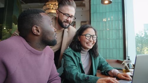 Diverse Colleagues Working on Laptop and Speaking in Cafe