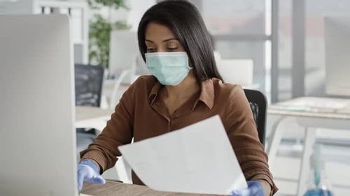 Masked Office Workers Reviewing Documents at Computer Desks