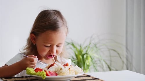 Una niña pequeña come espaguetis en casa
