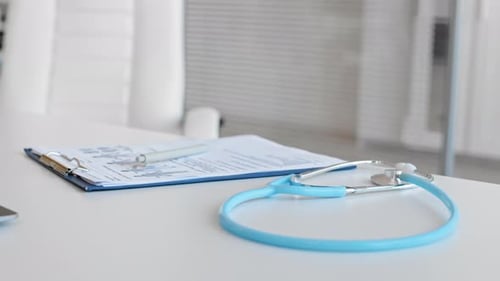 Doctor picks up stethoscope in clean examination room